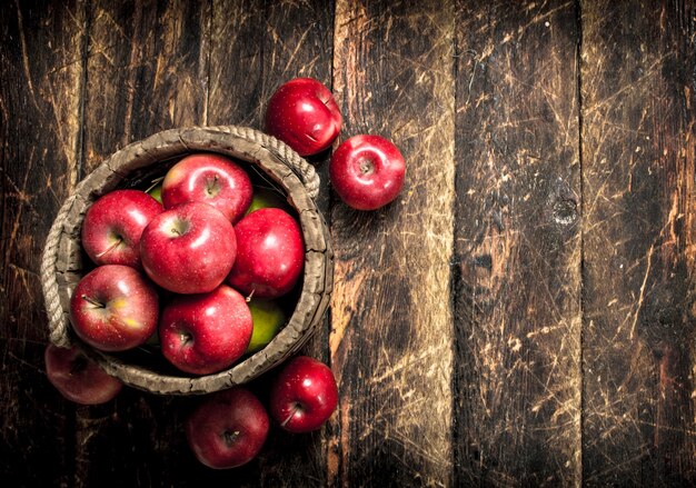 Rode rijpe appels in een houten emmer. Op een houten tafel.