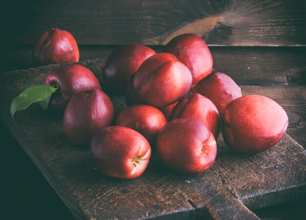 Rode rijpe perziken nectarine op een bruin houten bord