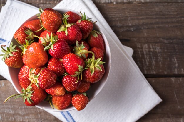 Rode rijpe sappige aardbei in een plaat, over oud bruin hout