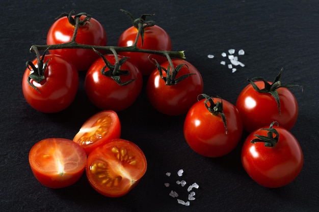 Rode rijpe tomaten en groot zeezout op een zwarte achtergrond