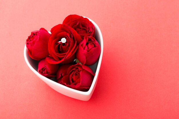 Rode roos en diamanten ring in hartvorm kom over de rode achtergrond
