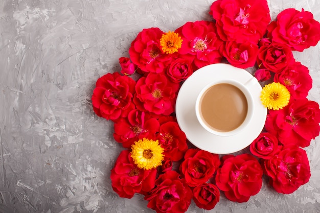 Rode roze bloemen en een kopje koffie. bovenaanzicht.