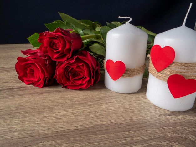 Rode rozen naast witte kaarsen en rode harten op tafel