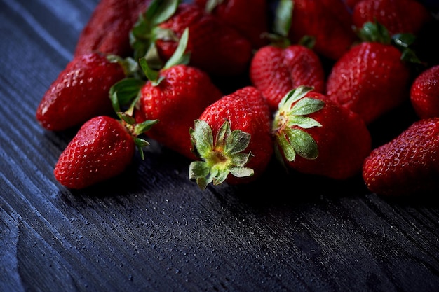 Rode, sappige aardbei op een donkere zwarte houten achtergrond de druppeltjes water sappigheid, vitamines en gezond voedsel