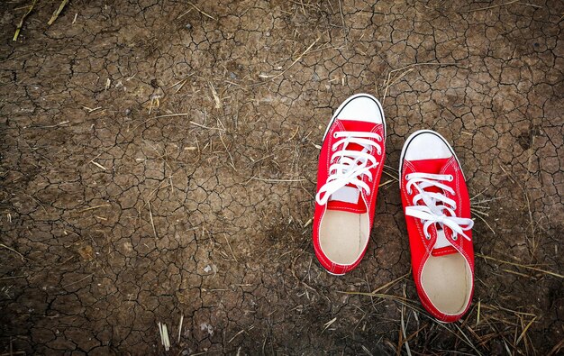 Rode schoenen witte schoenveters op gebarsten grond