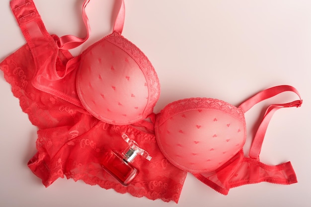 Rode sexy beha en slipje op roze achtergrond Dames sexy ondergoed set met rozen en parfum Cadeau-idee voor Vrouwendag of Valentijnsdag met kopieerruimte Verrassing voor mannen of voor hem Bovenaanzicht