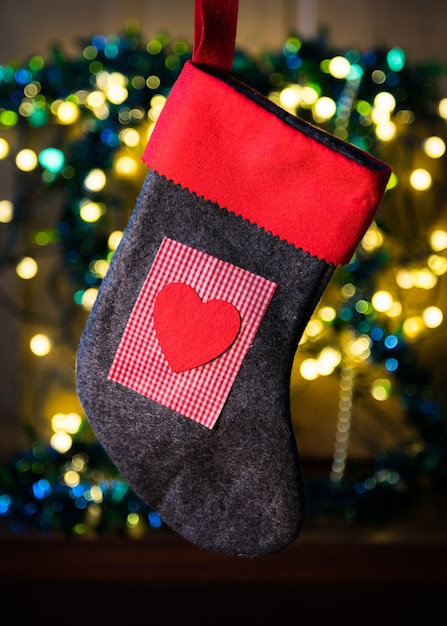 Rode sok met hart tussen kerstverlichting en kleurrijke versieringen op de achtergrond
