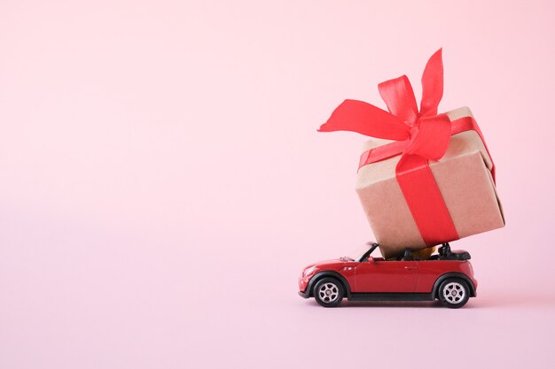 Foto rode speelgoedauto die giftdoos met rood lint levert