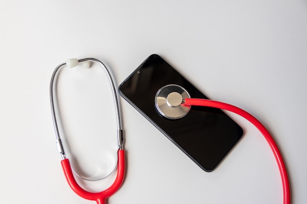 Rode stethoscoop op zwarte smartphone vertegenwoordigt gezondheidsdossiers digitale patiëntendossiers mobiele apparaten