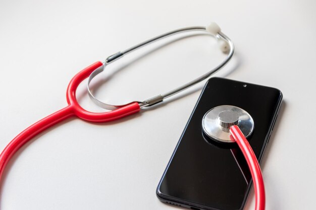 Rode stethoscoop op zwarte smartphone vertegenwoordigt gezondheidsdossiers digitale patiëntendossiers mobiele apparaten