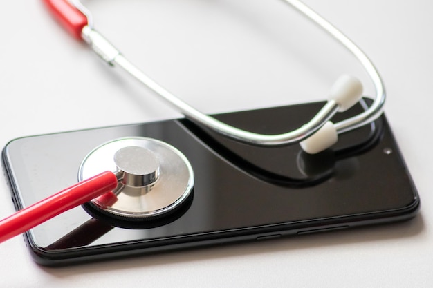 Rode stethoscoop op zwarte smartphone vertegenwoordigt gezondheidsdossiers digitale patiëntendossiers mobiele apparaten