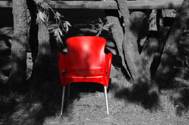 Foto rode stoel bij de bomen op het grasveld