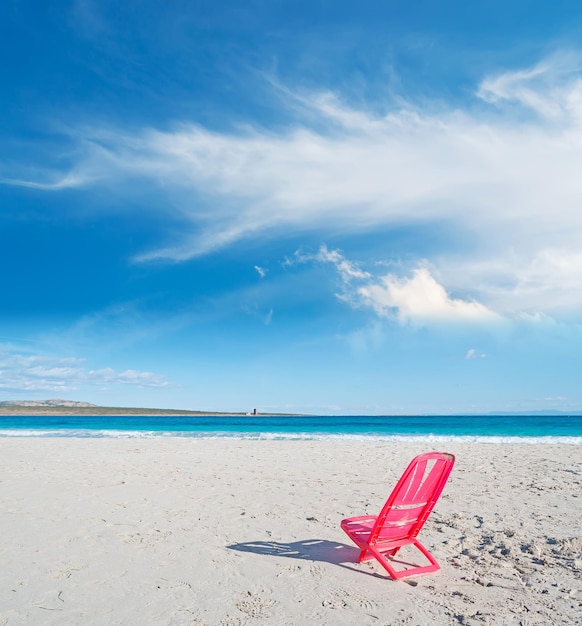 Rode stoel op het strand van La Pelosa op een bewolkte hemel