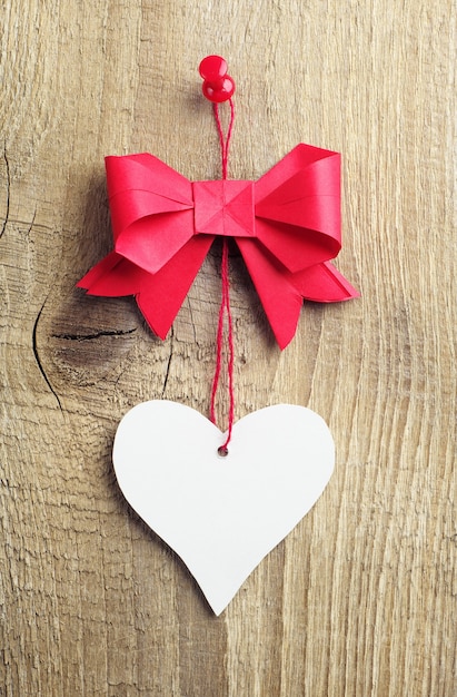 Rode strik met een hart van papier op een houten ondergrond