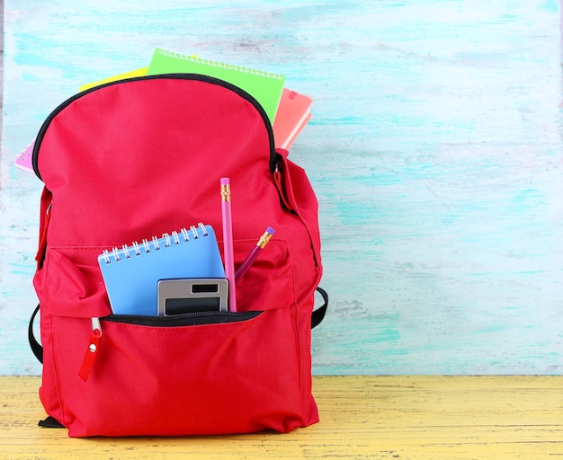 Rode tas met schoolapparatuur op houten achtergrond