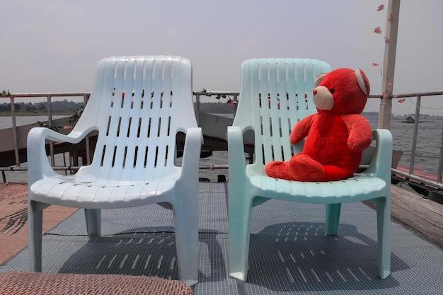 Foto rode teddybeer op een stoel in een zeilboot op het meer