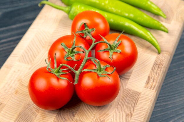 Rode tomaten en groene hete pepers op een keukenraad