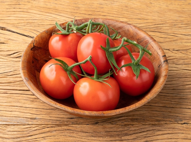 Rode tomaten in een kom boven houten tafel