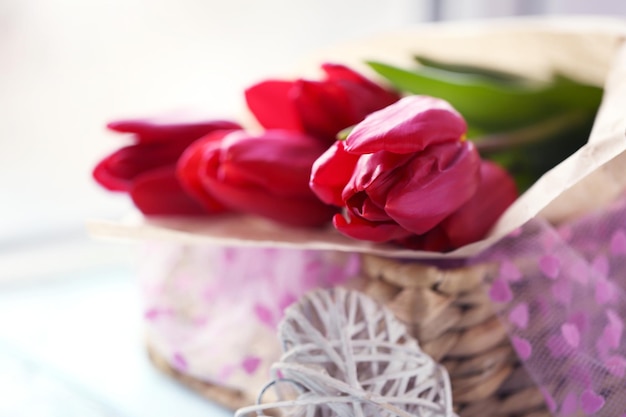 Rode tulpen in een rieten mand op een lichtblauwe tafel