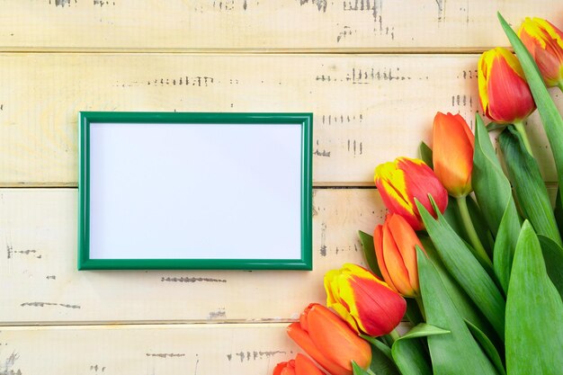 Rode tulpen op beige achtergrond en groene fotolijst