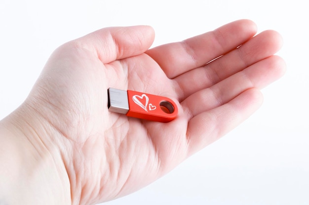 Rode USB-flashgeheugen met twee harten in de hand op een witte achtergrond