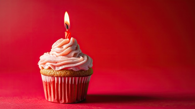 Rode verjaardagscupcake met roze glazuur en aangestoken kaars