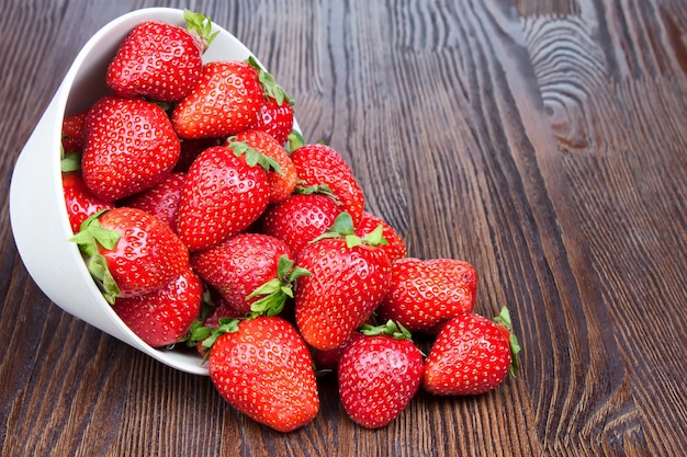 Rode verse aardbeien in een kom op bruine houten achtergrond