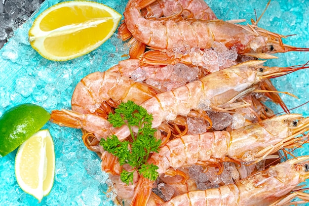 rode verse garnalenlangoustines met en zonder kop, liggen op de ijsblauwe zeeachtergrond, kers