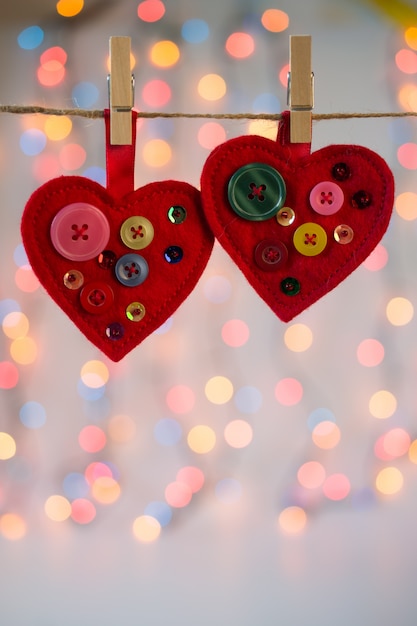 Rode vilten harten ambachten versierd met kralen en knopen met lichten. Valentijnsdag decor.