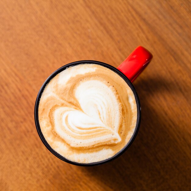 Rode vintage kopje latte art koffie op houten tafel in bovenaanzicht