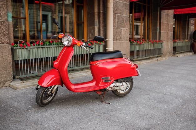 Rode vintage scooter geparkeerd op stoep van lege stad straat.