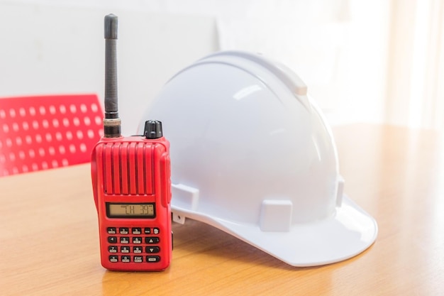 Rode walkietalkie-radio en een witte veiligheidshelm op houten achtergrond