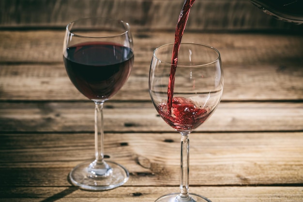 Rode wijn in een glas gieten op houten ondergrond