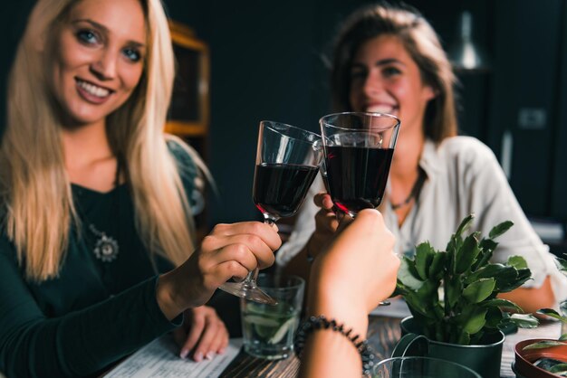 Rode wijn roosteren Vrouwelijke vrienden roosteren met rode wijn Plezier met water op tafel