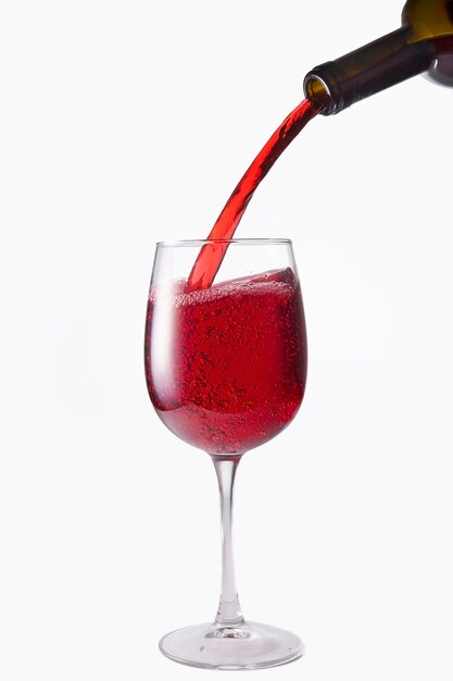 Rode wijn wordt uit een fles in een glas gegoten, isoleer op een witte achtergrond