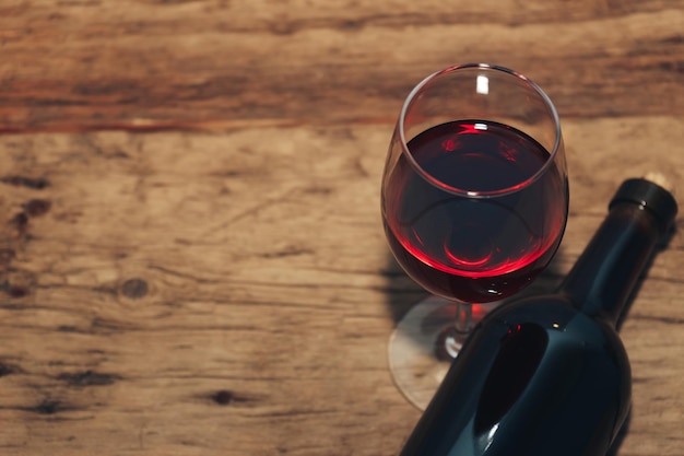 Rode wijnfles en glas wijn op een oude houten tafel