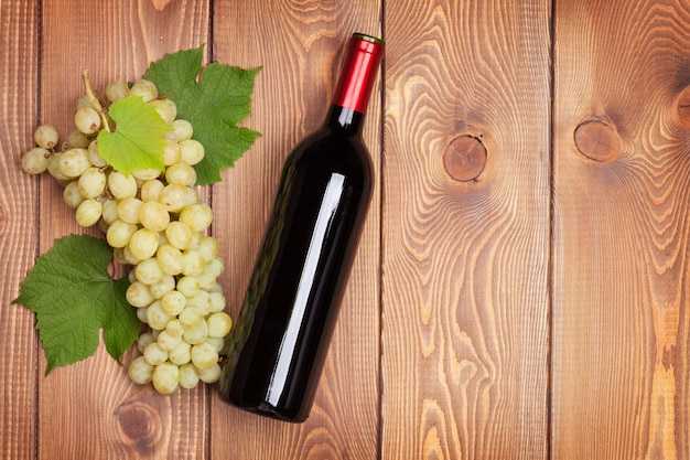 Rode wijnfles en tros witte druiven