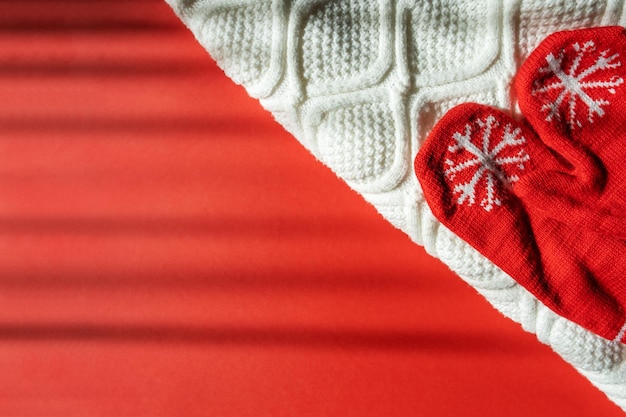 Rode winter wanten en witte gebreide trui op een rode achtergrond. Ruimte kopiëren. Concept Kerstmis en Nieuwjaar.