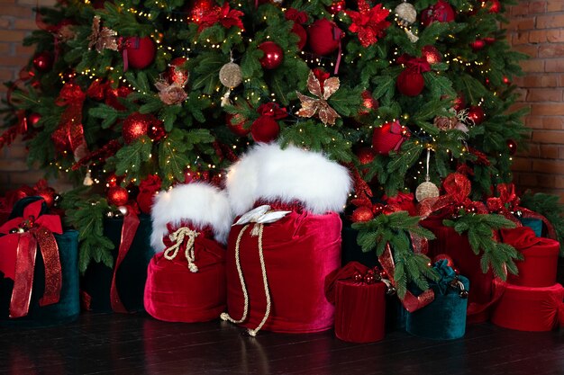 Rode zak zak kerstman met geschenken bij de kerstboom in de woonkamer