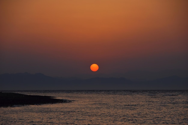 Rode zon bij zonsopgang aan zee op vakantie