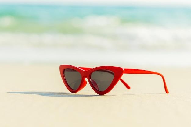 Rode zonnebril op het zand mooie zomerstrand