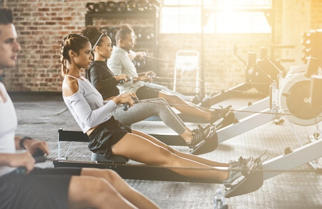 Roeimachinegroep en training in gymles of fitnesstraining of cardio-roeiteam en praktijk Mensen gezonde atleet en uitdaging op sportuitrusting rijploeg en sportclub