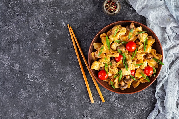 Roerbak de pasta met groenten, bloemkool en champignons. Bovenaanzicht