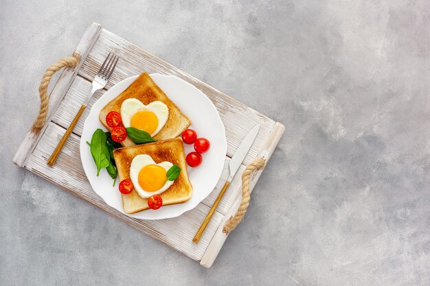 Roerei in de vorm van hart op plaat met tomaten, greens en koffie