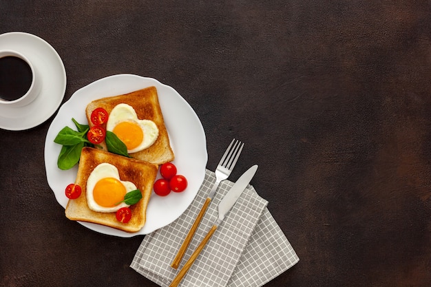 Roerei in de vorm van hart op plaat met tomaten, greens en koffie