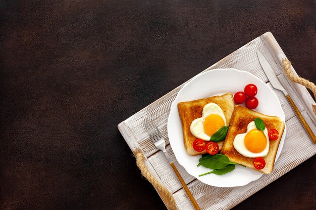 Roerei in de vorm van hart op plaat met tomaten, greens en koffie