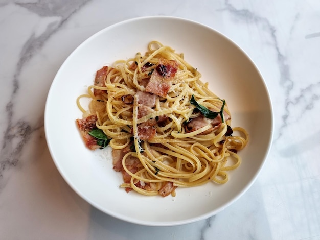 Roergebakken pasta linguine met gedroogde chili en krokante bacon op een wit bord