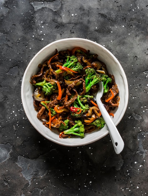 Roergebakken pittig rundvlees met broccoli, wortelen en chilipepers op een donkere achtergrond bovenaanzicht