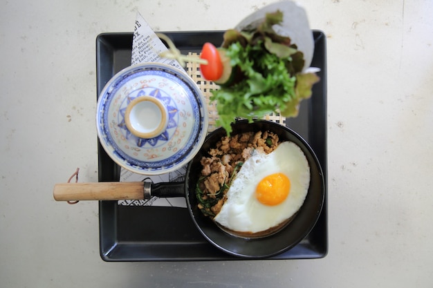 Roergebakken varkensvlees en basilicum geserveerd met rijst en gebakken ei, thais eten