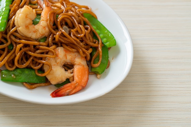 roergebakken yakisoba-noedels met doperwtjes en garnalen. Aziatische eetstijl